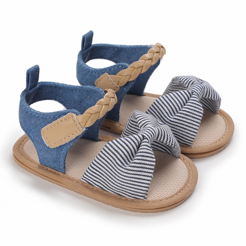 A pair of blue and beige braided baby first walker sandals with soft anti-slip soles.