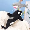 A black and white killer whale plush toy is shown next to a gray great white shark plush toy.