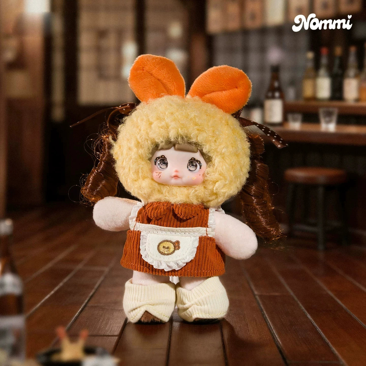 A fluffy orange-eared plush keychain of a girl with brown hair wearing an orange outfit.