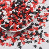 A pile of red, white, and black cartoon polymer clay slices for slime and craft projects.