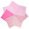 A stack of seven pink cotton fabric squares with various floral and polka dot patterns for quilting