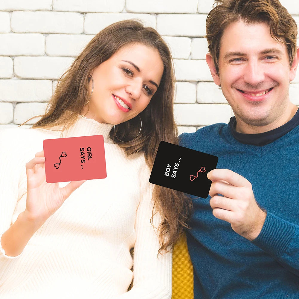 A woman and a man holding scratch-off cards that say Girl says and Boy says for a couples challenge.
