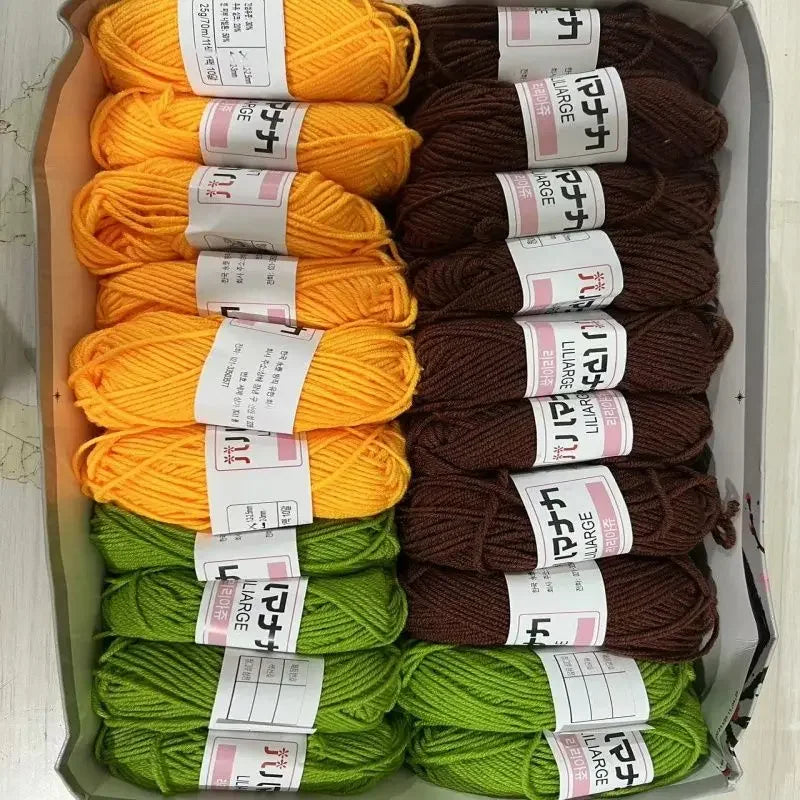 A collection of yarn in various shades of orange, yellow, and green is displayed in a box.