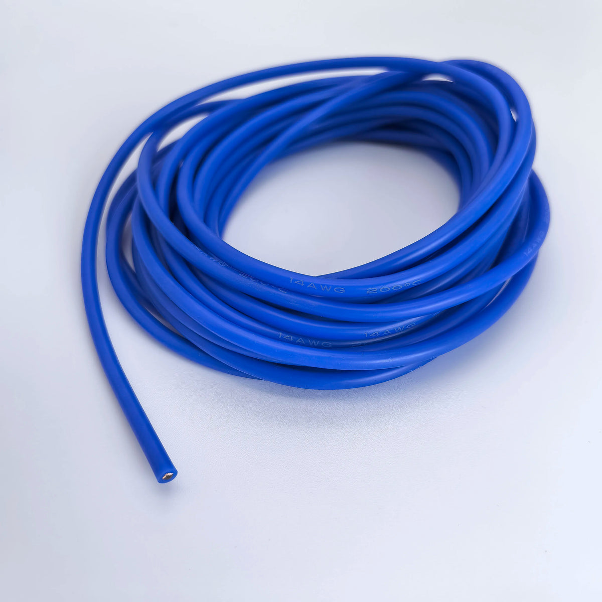 A coil of blue flexible silicone tinned copper wire with multiple AWG gauges lying on a white surface.