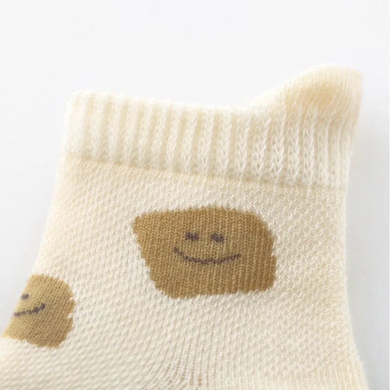 A cream-colored sock featuring a smiling brown toast cartoon design.
