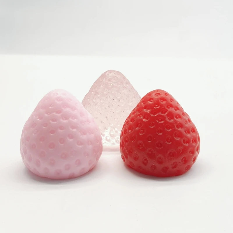 Three squishy fidget toys shaped like strawberries in pink, clear, and red colors