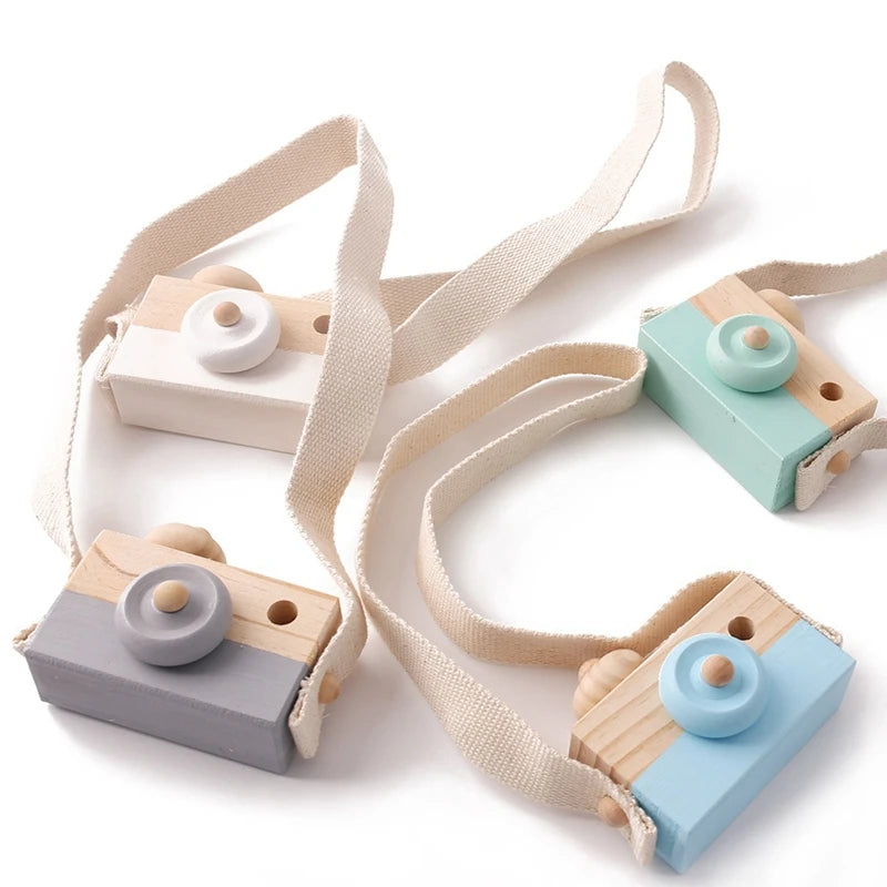 Montessori wooden camera teether toy with light wood and pastel colored plastic body and strap
