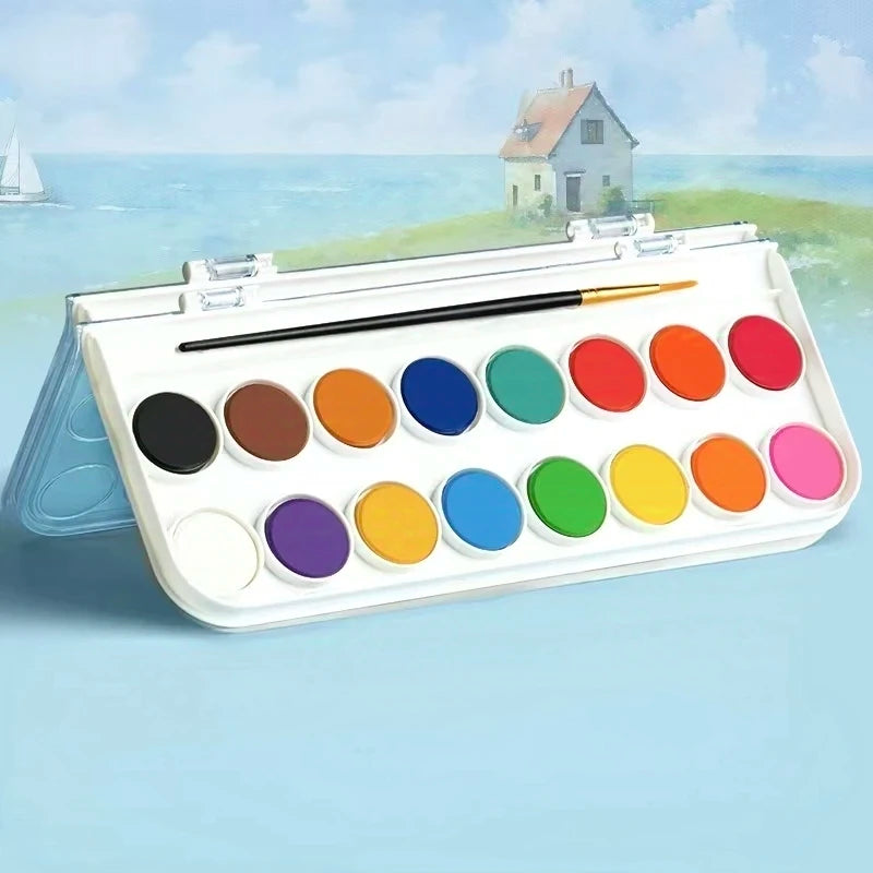 A portable watercolor paint set with various colored paints and a brush displayed outdoors against a scenic background.