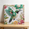 A diamond painting featuring a vibrant green and black bird adorned with sparkling pearls and gemstones.