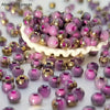 A pile of vibrant round beads in shades of purple and gold for jewelry making
