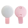 A pink portable LED selfie ring light with a clip attached to the base.