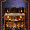 A detailed miniature library model built from wood and glass with internal LED lighting.
