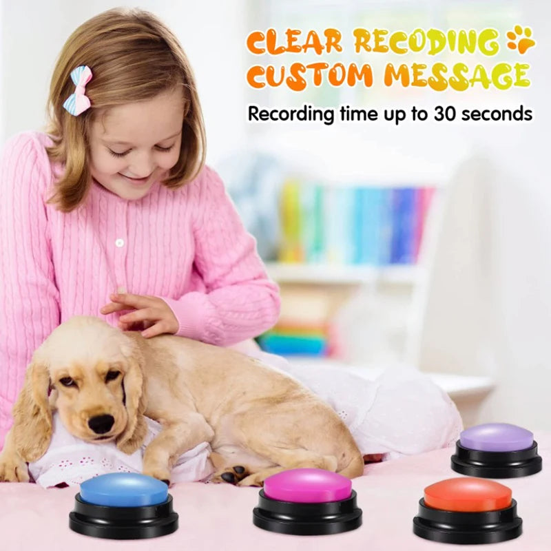 A yellow dog lies next to a pink sweater and various colored recording buttons on a table.