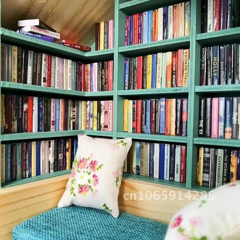 A wooden bookshelf filled with miniature books and decorated with a pink floral pillow.