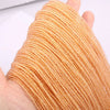 A hand holds a strand of faceted natural stone beads in a warm golden-orange color.