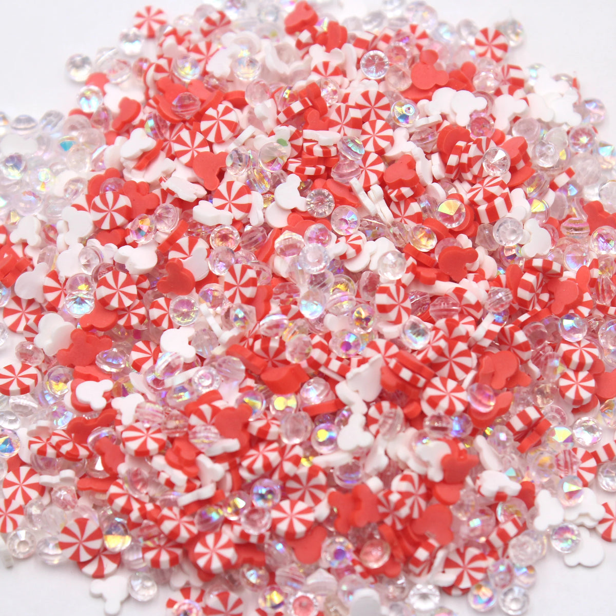 A pile of small, translucent polymer clay slices in red and white patterns for slime and craft projects.