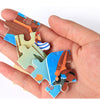 A hand holds together several wooden jigsaw puzzle pieces shaped like animals and vehicles.
