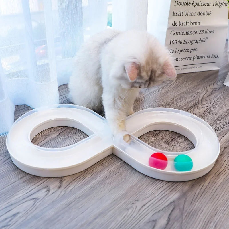 A fluffy white cat is interacting with a white, oval-shaped toy featuring colored buttons.