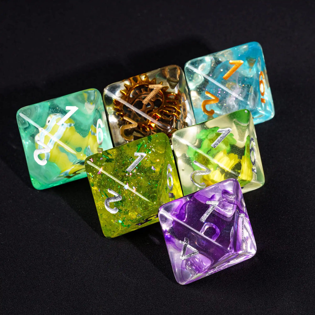 A collection of seven polyhedral resin dice in various colors including green blue yellow and purple