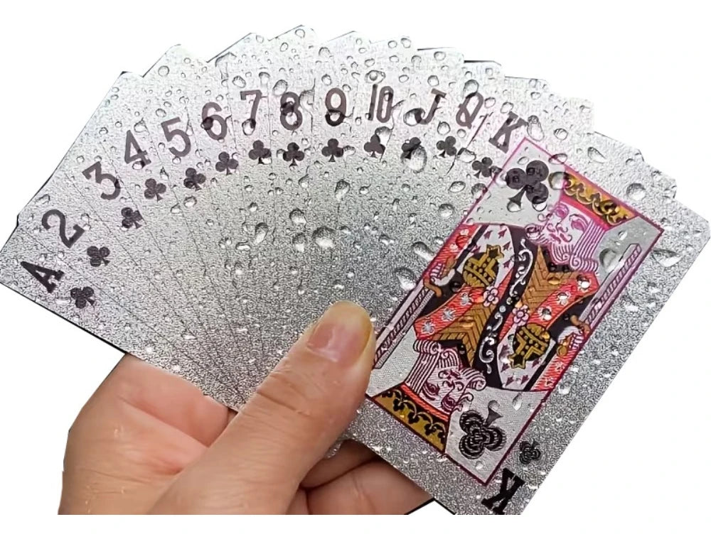 A hand holds a fan of luxury gold foil playing cards showing the Ace through King suits.