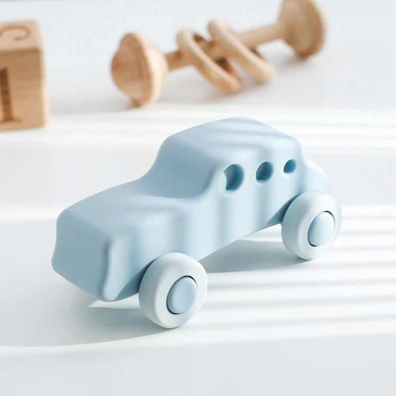 A light blue silicone baby teether toy shaped like a cartoon car with wheels