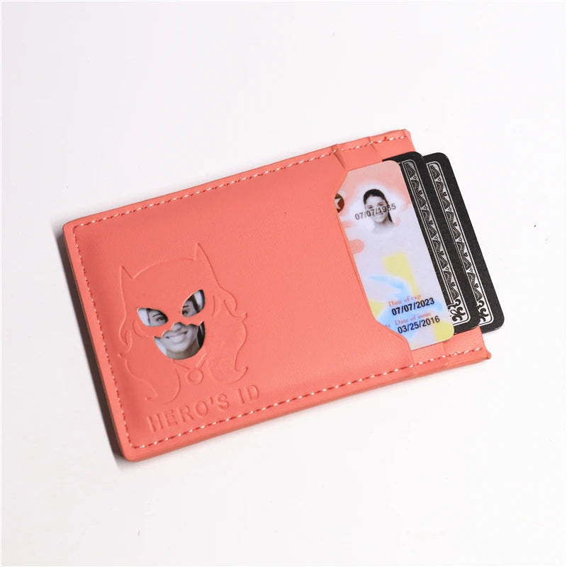 A pink card holder wallet featuring a cat superhero design and holding several cards.