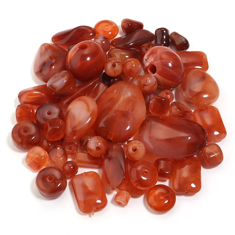 A pile of colorful, translucent amber and reddish-brown acrylic beads for jewelry making.