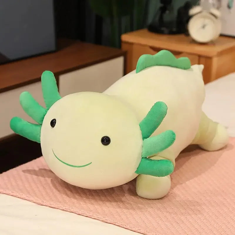 A soft, light yellow and green axolotl plush pillow with large fins resting on a pink surface.