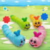 A collection of colorful wind-up caterpillar crawling toys in various shades of green, yellow, blue, and pink on a grassy bac