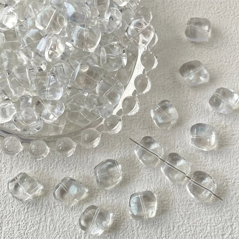 A pile of clear geometric glass beads in irregular square shapes for jewelry making