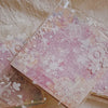 A sheet of textured pink paper decorated with white snowflakes and floral elements for junk journals