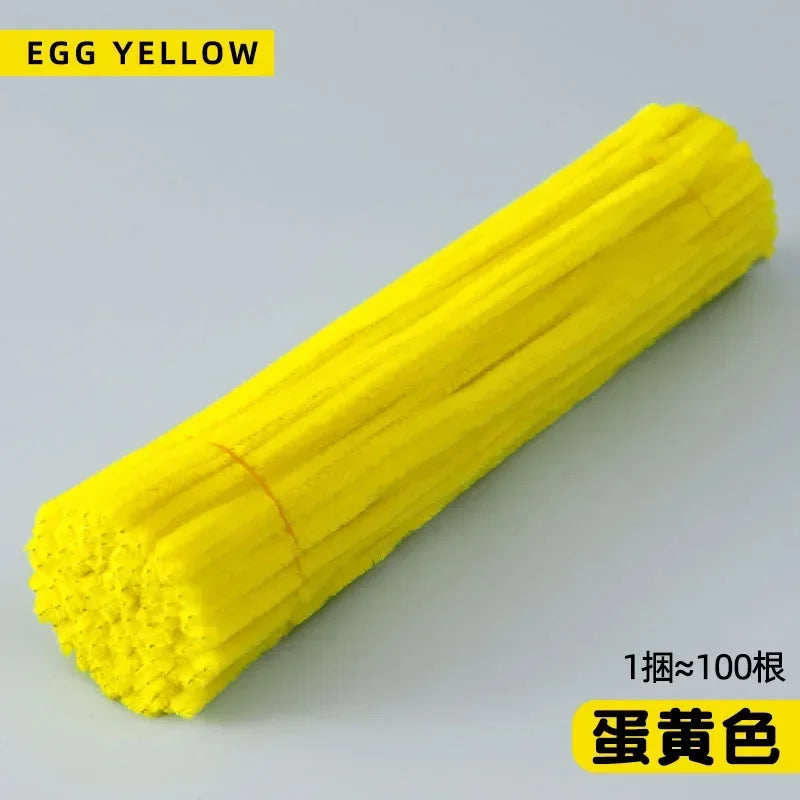 A bright yellow chenille stem is shown diagonally against a light gray background.