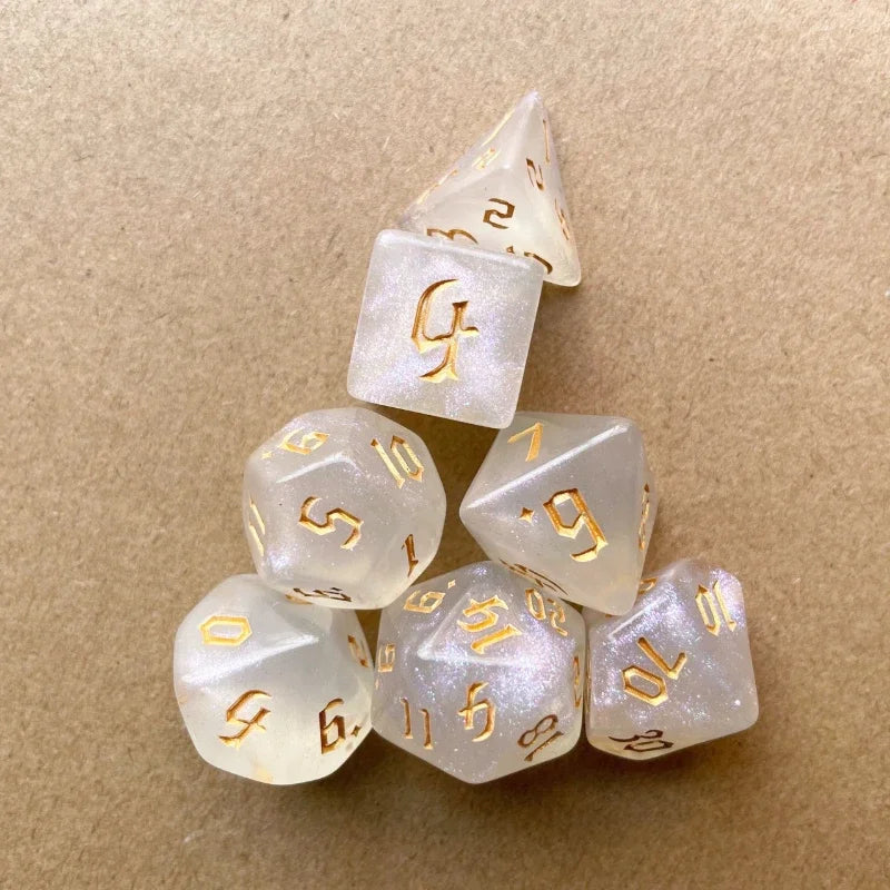 A stack of seven glitter gold polyhedral dice showing various numbers and angles on a brown surface.