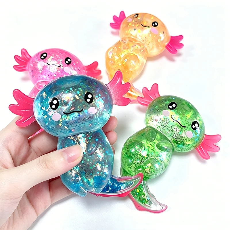 A hand holds several glitter axolotl squishy stress relief toys in pink, orange, and green colors.