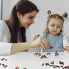 A woman is helping a young girl assemble a wooden jigsaw puzzle featuring various animal shapes.