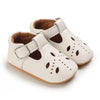 A pair of white lace-trimmed baby girl moccasin shoes with a bow shown from the side.