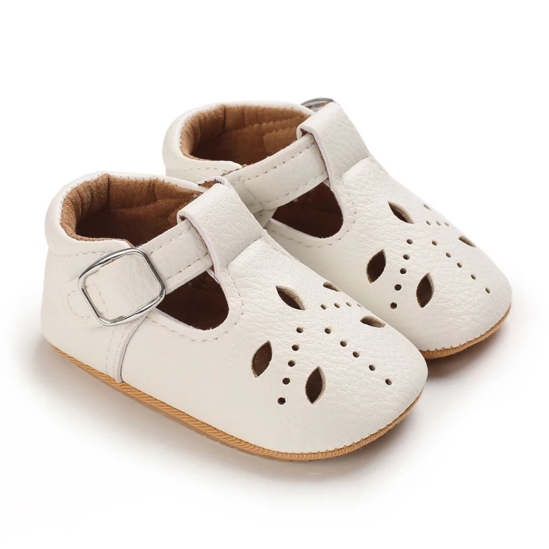 A pair of white lace-trimmed baby girl moccasin shoes with a bow shown from the side.