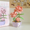 A miniature flower bouquet made of pink and green building blocks displayed next to its packaging.