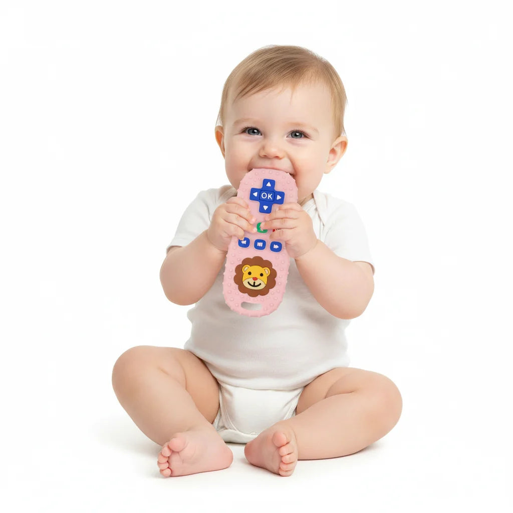 A baby is holding a pink lion-shaped silicone teether with remote control design.