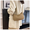 A beige PU square crossbody bag with a gold chain strap is shown against a dark cabinet.