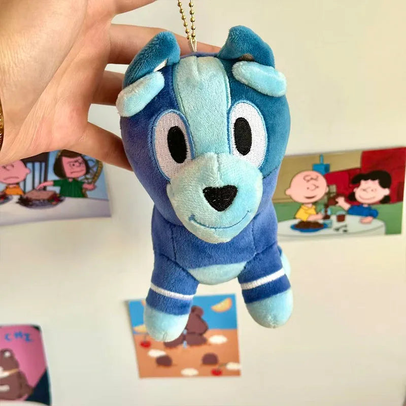 A hand is holding a blue plush doll resembling a dog character from Bluey.