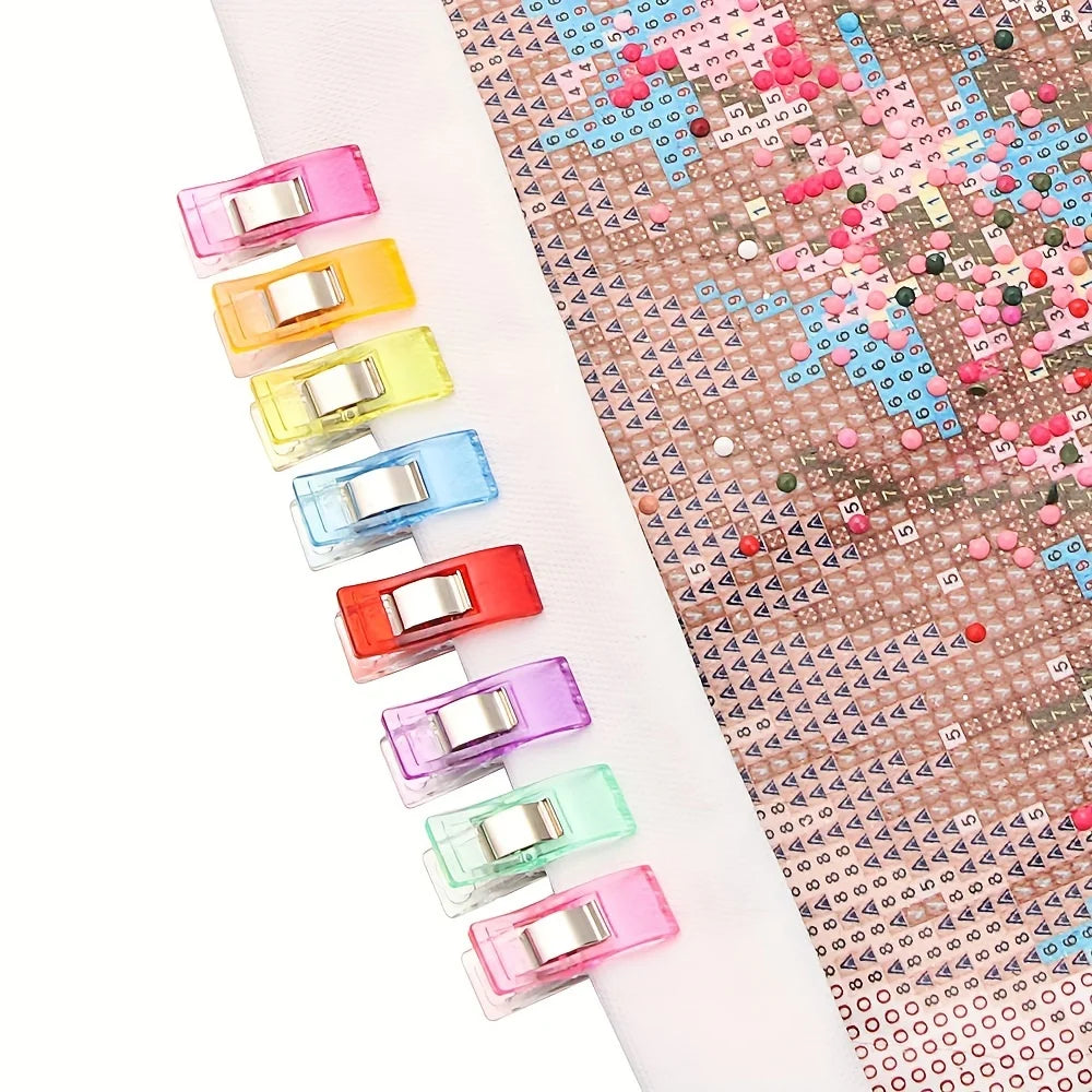 An 8-piece set of diamond painting clips in various pastel colors arranged in a line.
