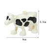 A white and black cow shaped building block with a cylindrical head, measuring 5.3 cm high and 9 cm long.