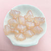A collection of translucent pink and peach shimmer mermaid bowknot beads arranged in a white dish.
