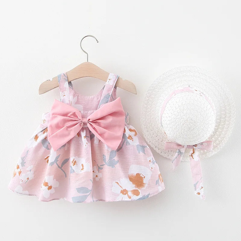 A pink floral baby girl summer dress and sunhat set with bow details displayed on a hanger.