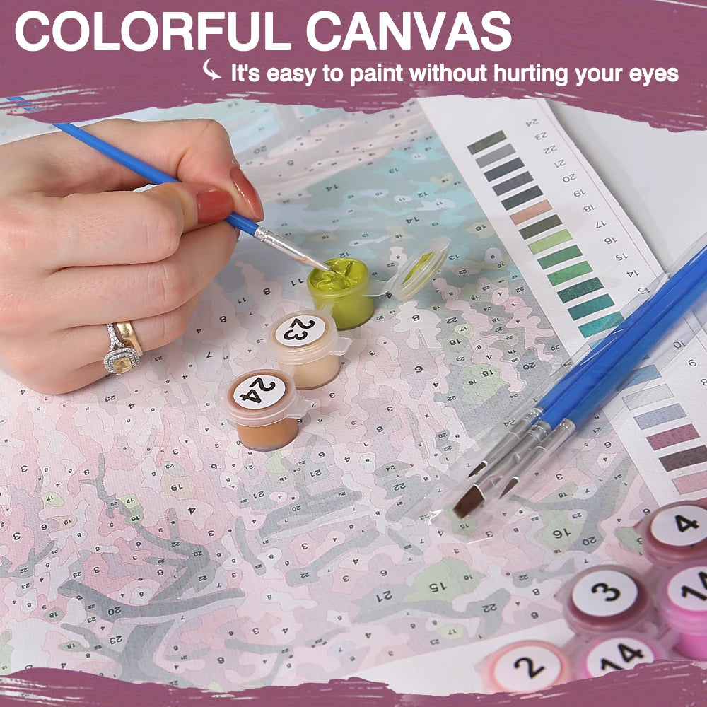 A hand paints a canvas with small paint pots and a brush on a map background for a DIY paint by numbers kit.