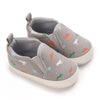Gray baby first walker sneakers with a cute dinosaur print featuring orange, green, and white dinosaurs.