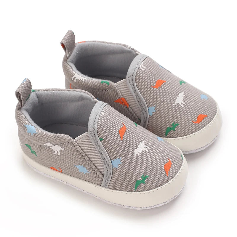 Gray baby first walker sneakers with a cute dinosaur print featuring orange, green, and white dinosaurs.