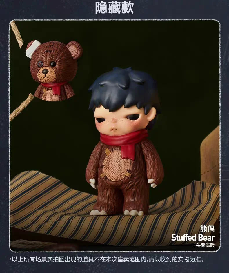 A collectible figurine of a dark-haired character wearing a red scarf and brown clothing, with a small teddy bear accessory a