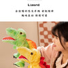 Une femme tient un jouet marionnette de dinosaure jaune, avec un dinosaure vert attaché, dans un décor rose pâle.